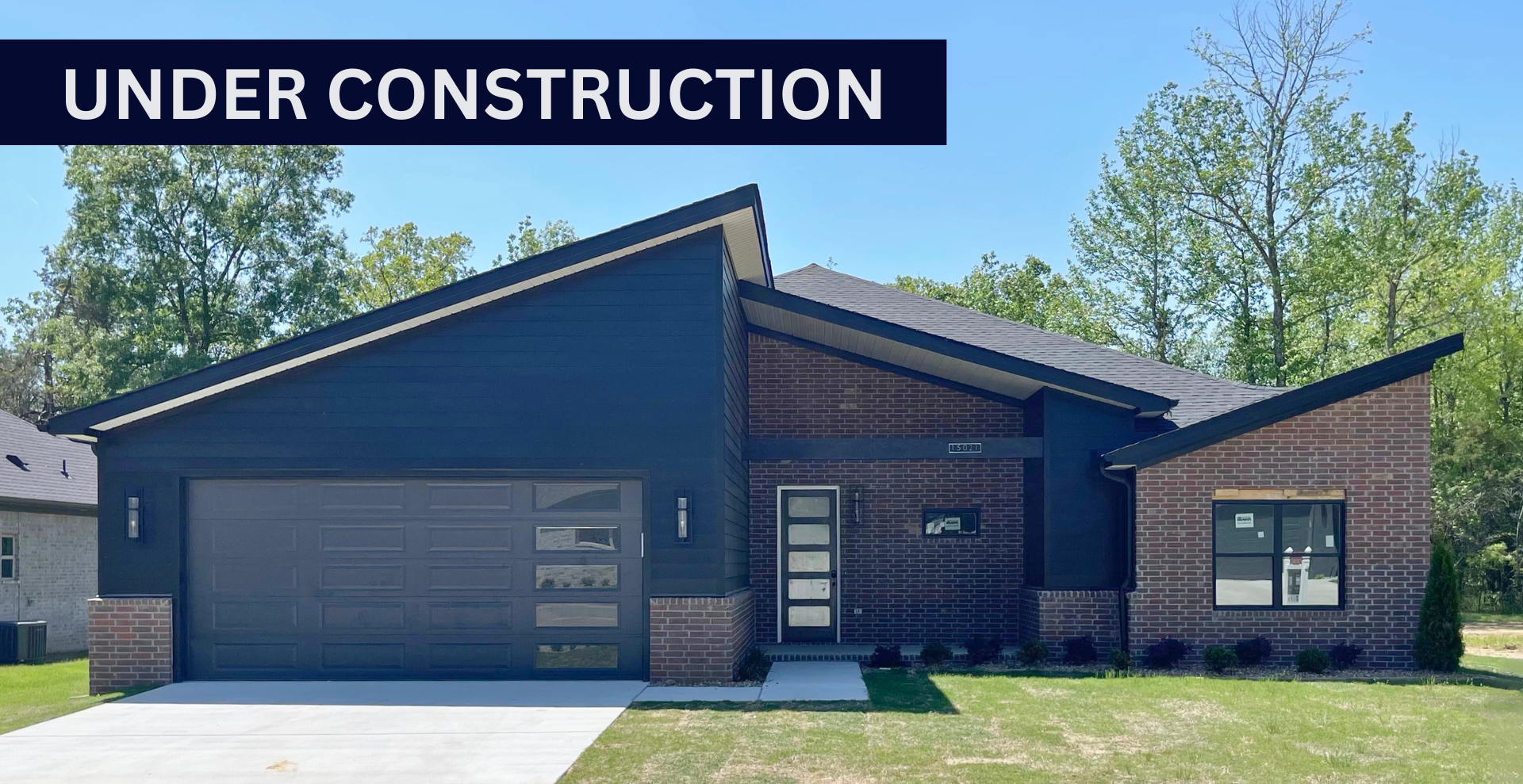Modern new construction home with black garage door and dark brick exterior