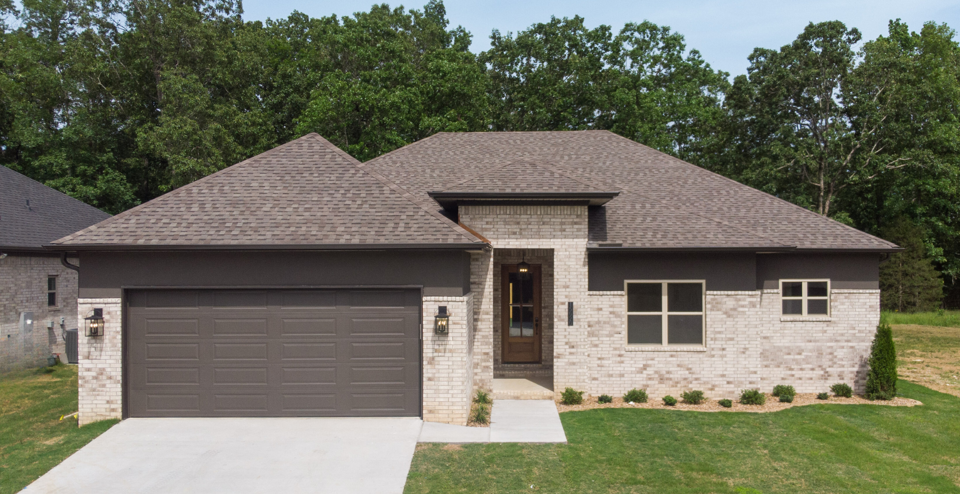 new construction home with dark roof, white garage door, and lighter brick. single level house