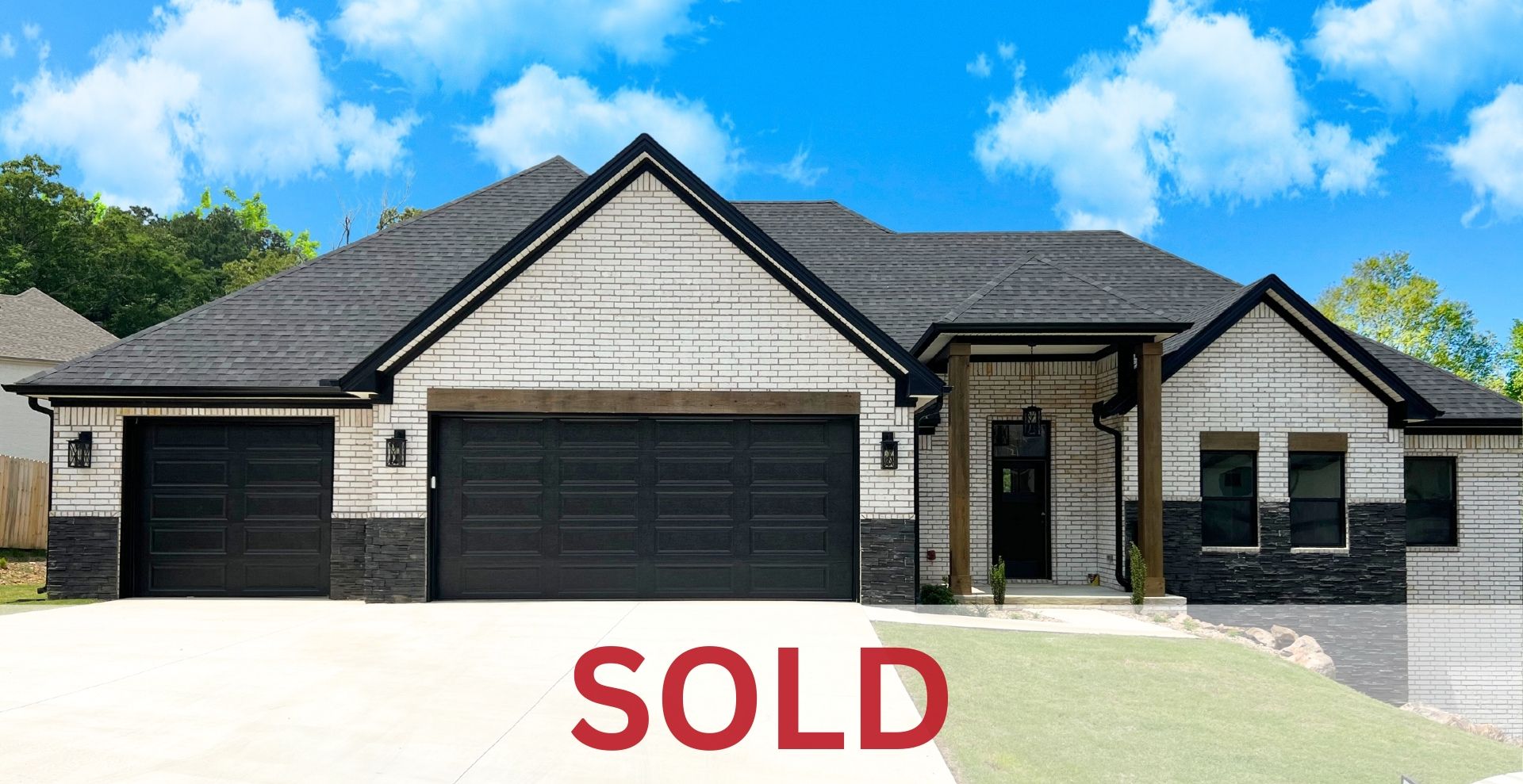 very modern new construction home with black garage door and white brick exterior with a square front porch by hines homes