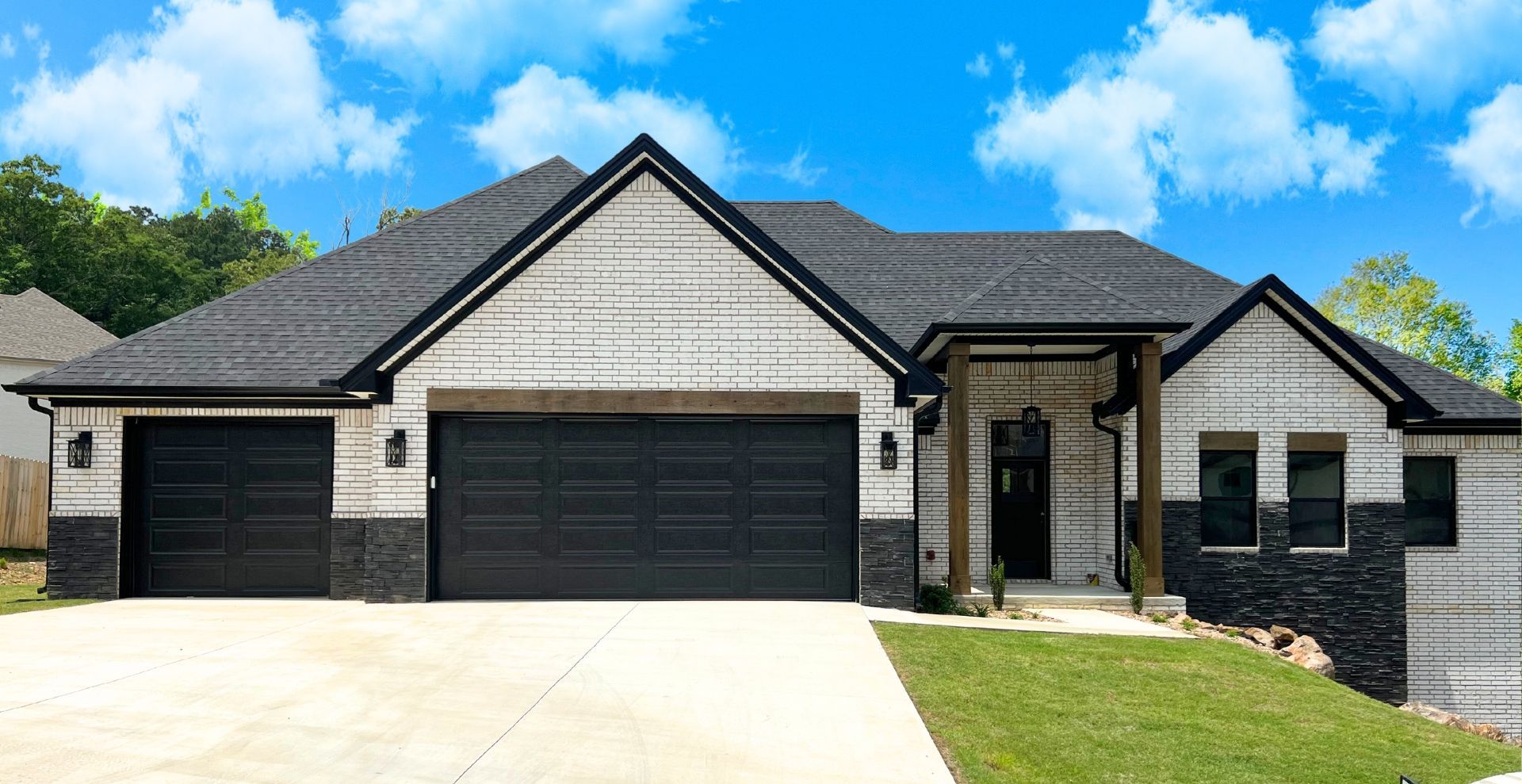 very modern new construction home with black garage door and white brick exterior with a square front porch by hines homes