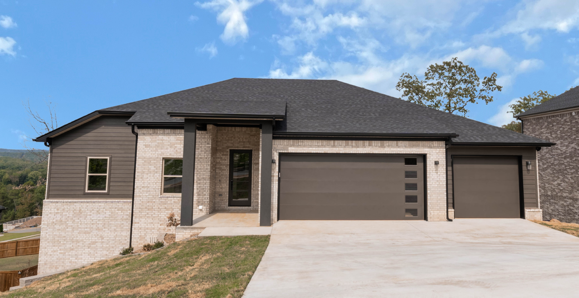 new construction home with brown garage door and light brick with a square front porch by hines homes