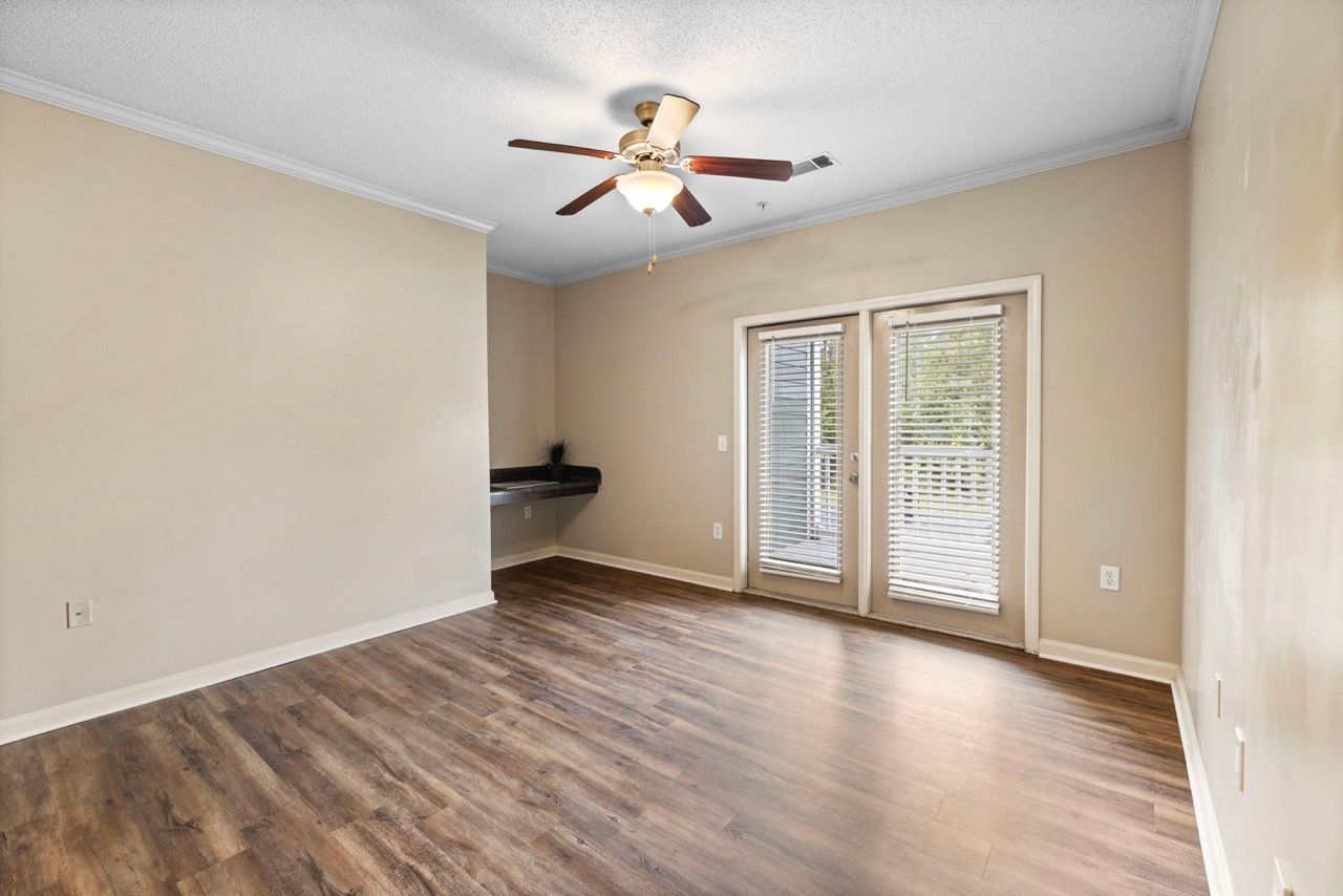 Living room with wood-like flooring, ceiling fan, and French doors with blinds.