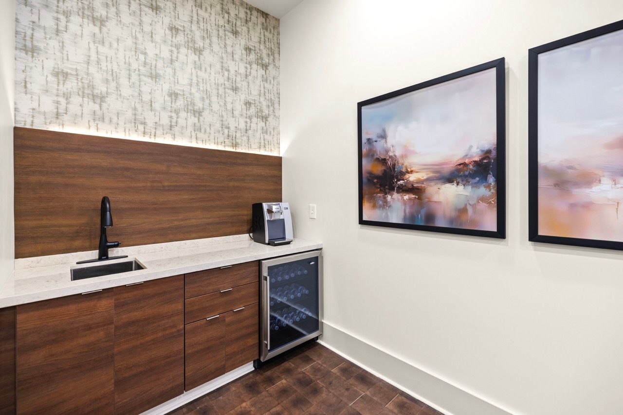 Kitchenette area with wood cabinets, stone countertop, sink, coffee machine, and wine cooler.