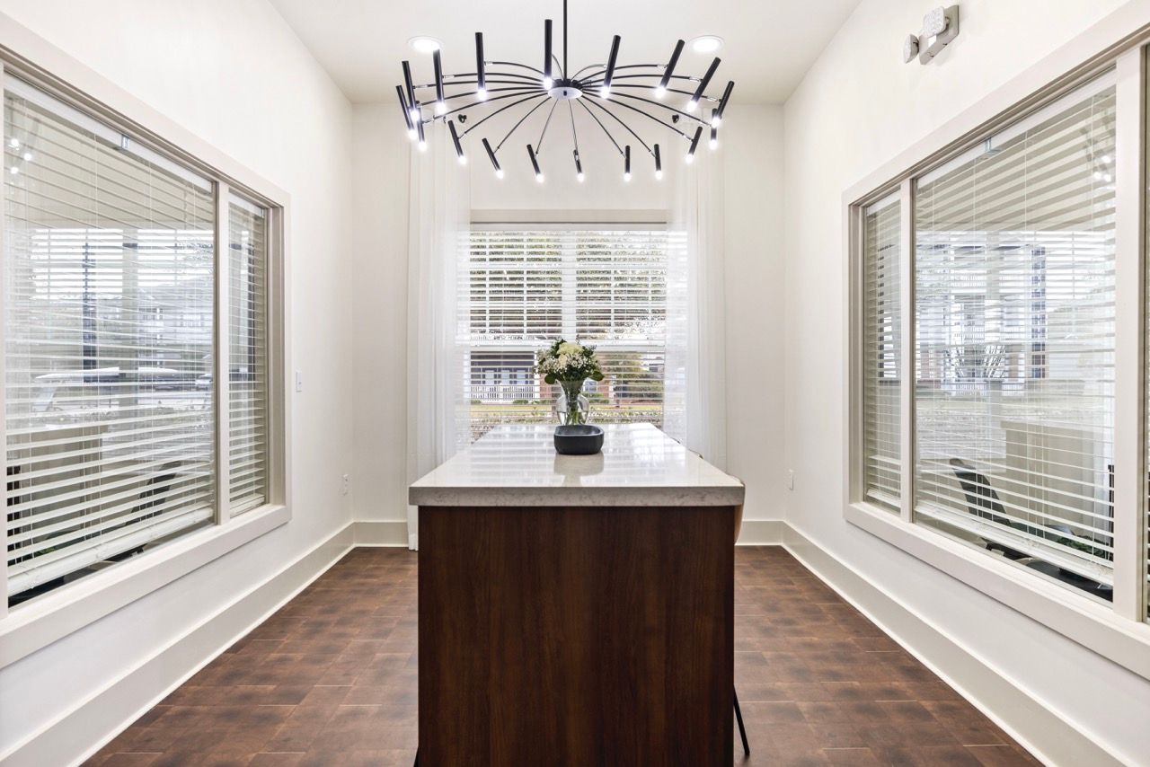 Bright modern kitchen with a central island, marble countertop, and large windows.