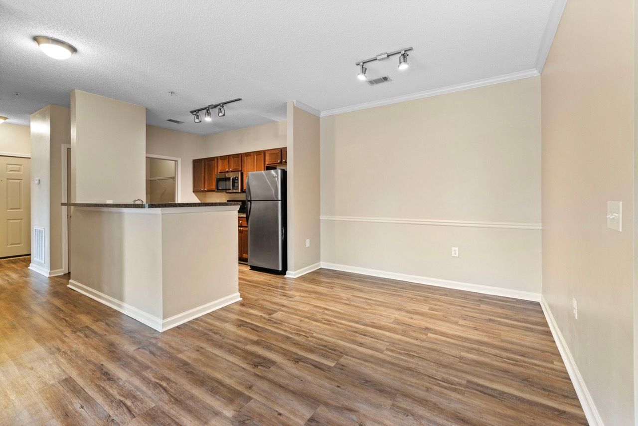 Open-concept living area with kitchen island, stainless steel fridge, and wood-look flooring.