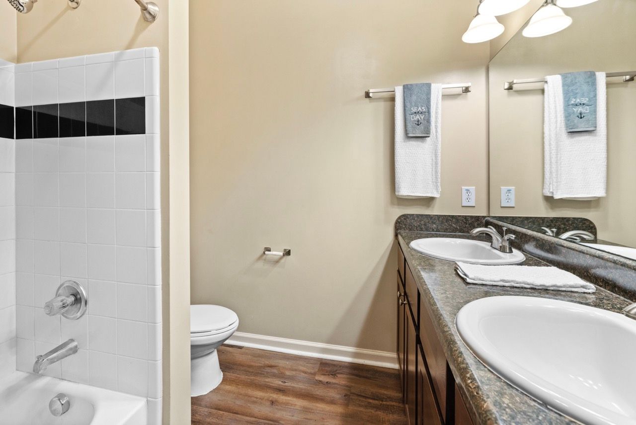 Bathroom with double-sink vanity, toilet, and tiled shower area.
