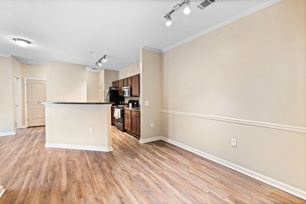 Open-concept apartment kitchen with an island, dark wood cabinets, stainless appliances, and wood-look flooring.