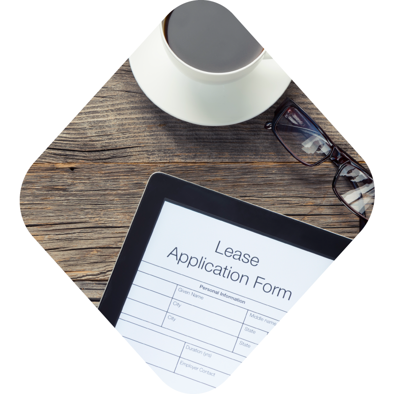 Photo of a tablet with a lease application on the screen on a desk with coffee and glasses, all encapsulated in a diamond shape