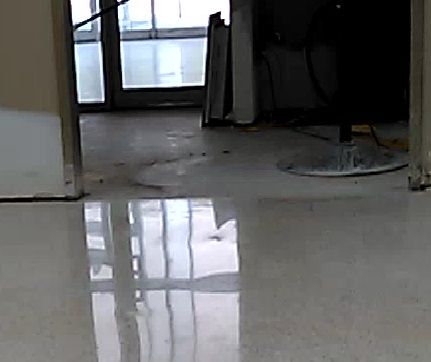 Empty hallway with a glossy floor reflecting windows and light.