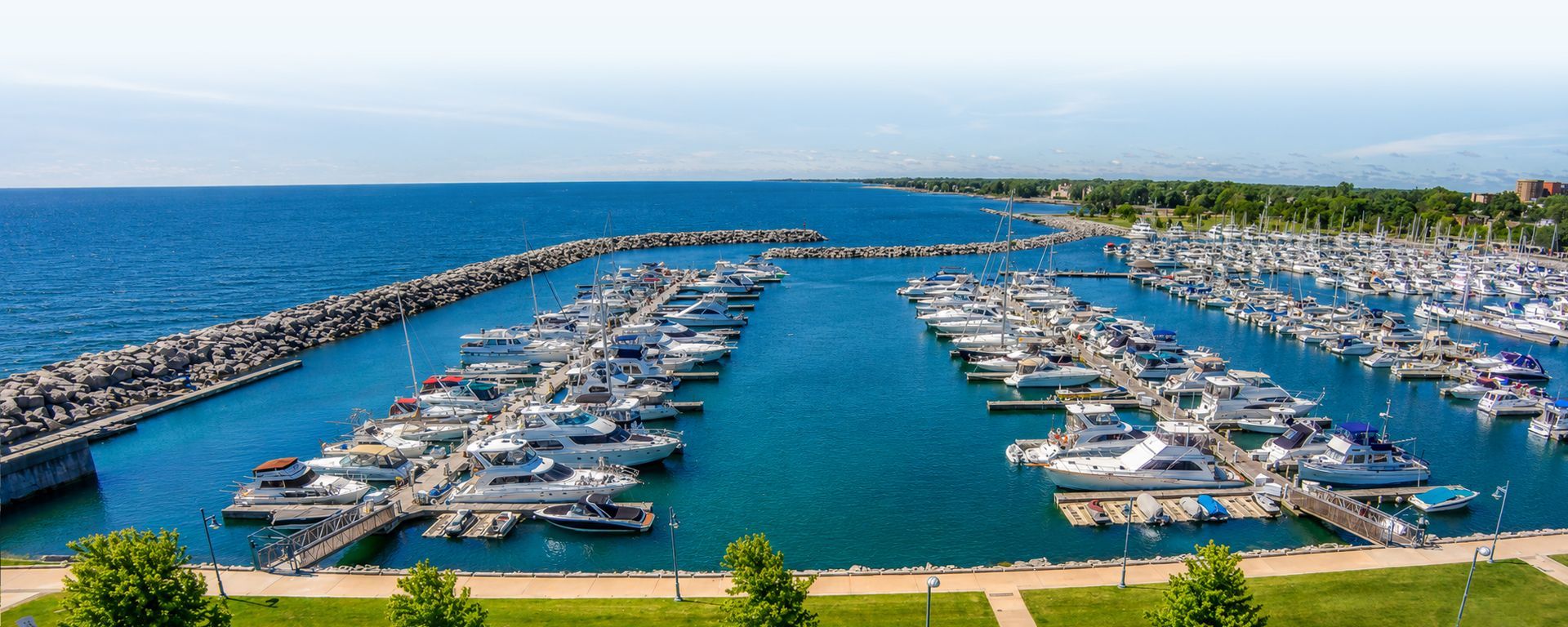 Marina packed with white boats beside blue ocean under a clear sky