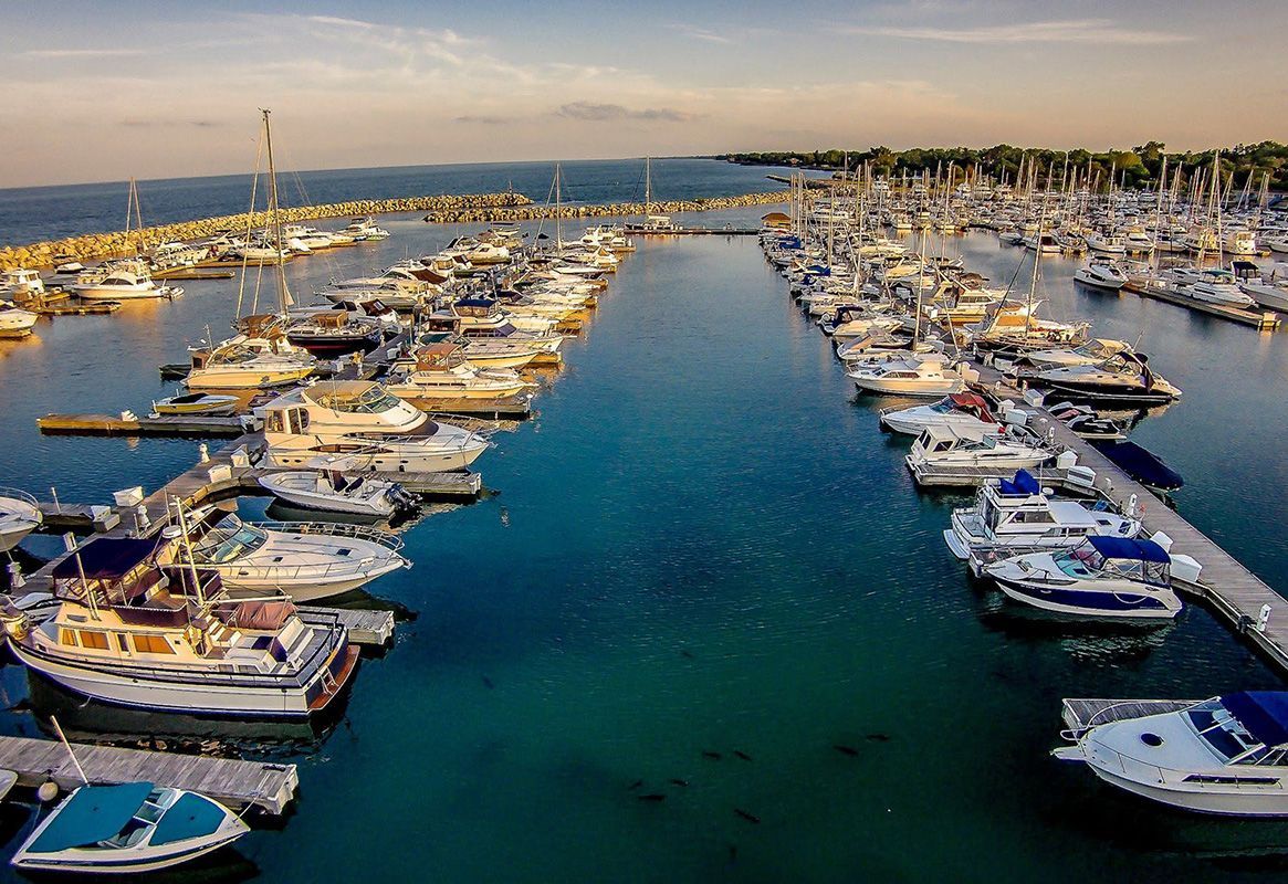 Marina with rows of docked boats in a calm blue harbor at sunset