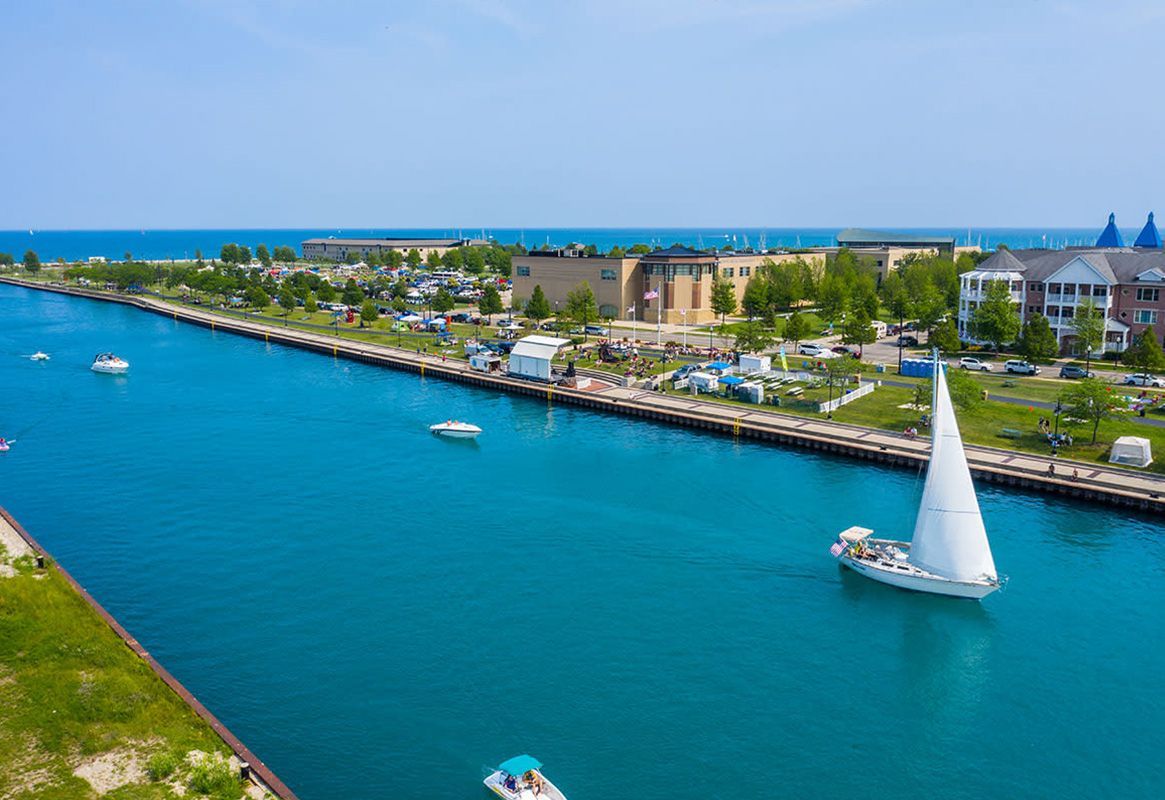 Canal with turquoise water, sailboats, and waterfront buildings under a clear blue sky