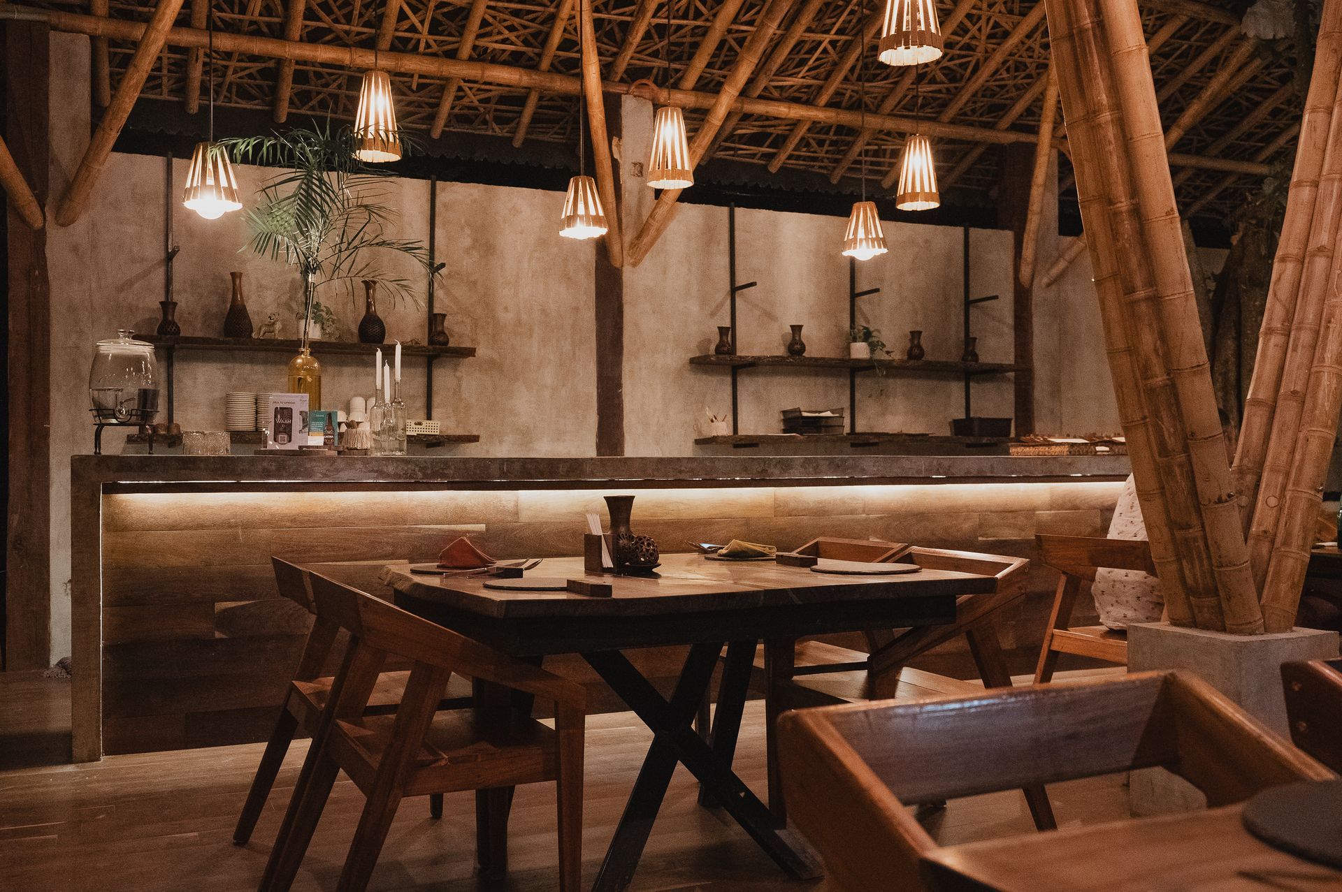 Acogedor interior del restaurante Waah Cocina de origen con estructuras de bambú, mesas y sillas de madera e iluminación suave.