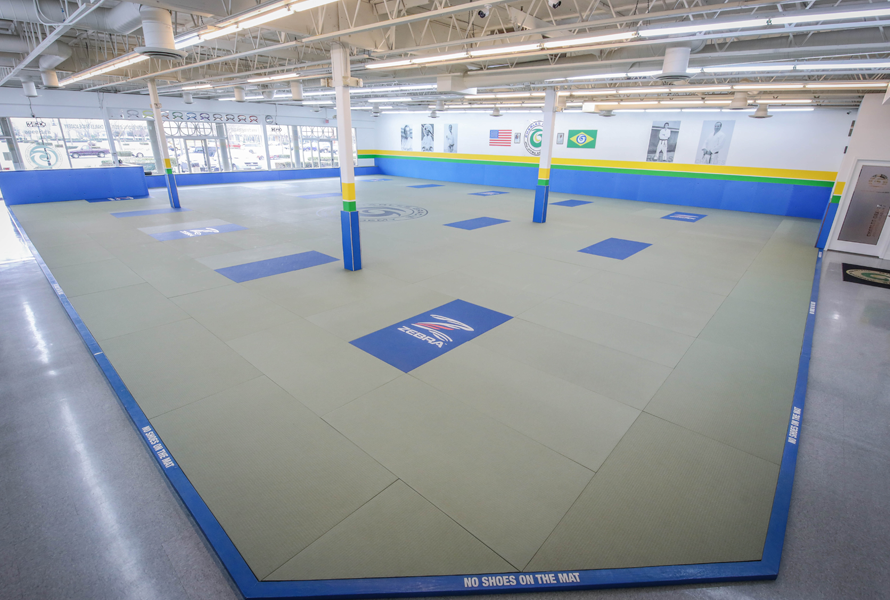 A large empty gym with a judo mat on the floor.