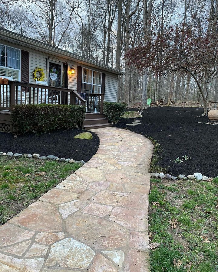A stone walkway leading to a house in the woods.