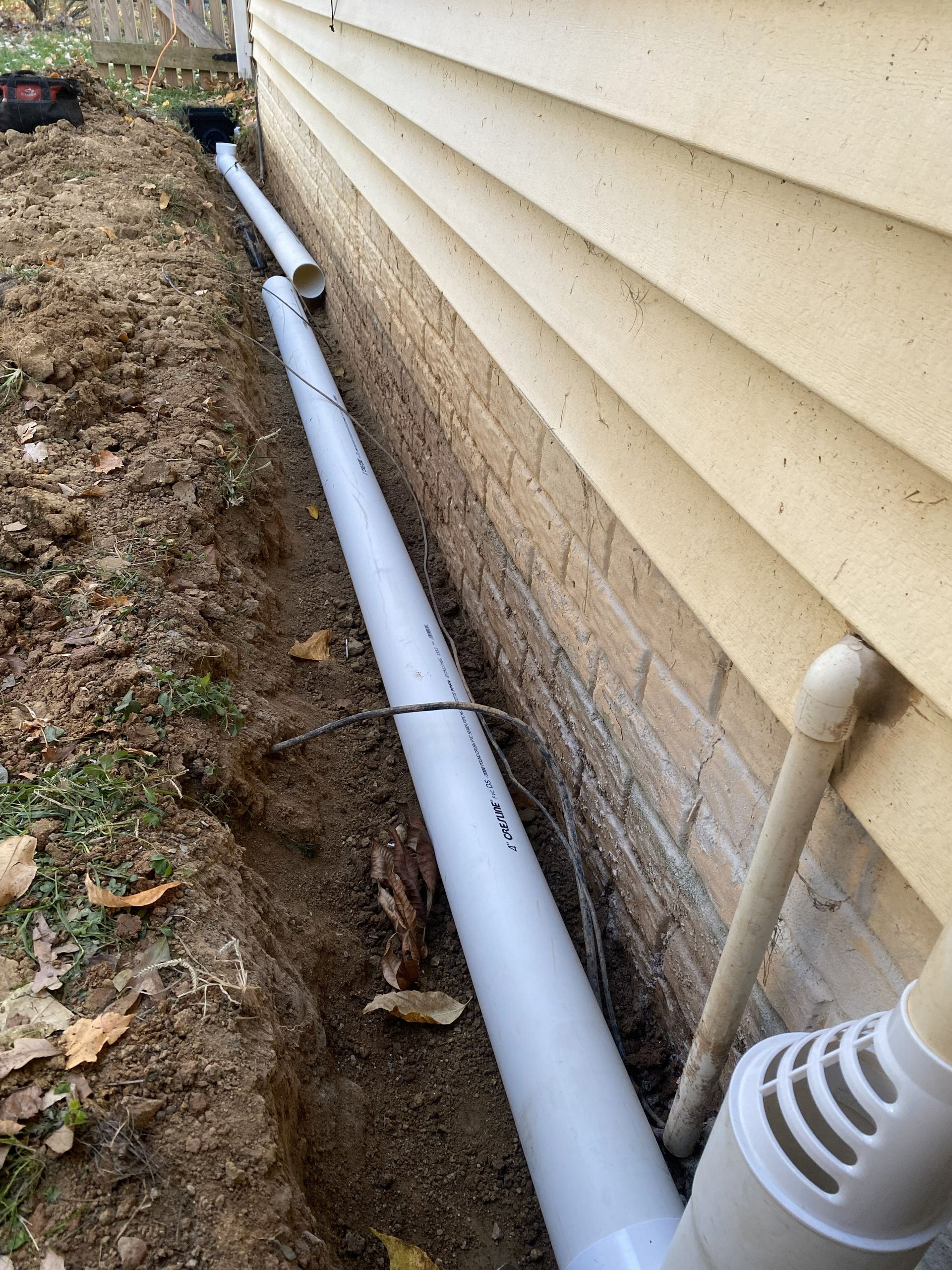 Stone patio with a built-in stone bench, garden, and up-lighting in a backyard at night.