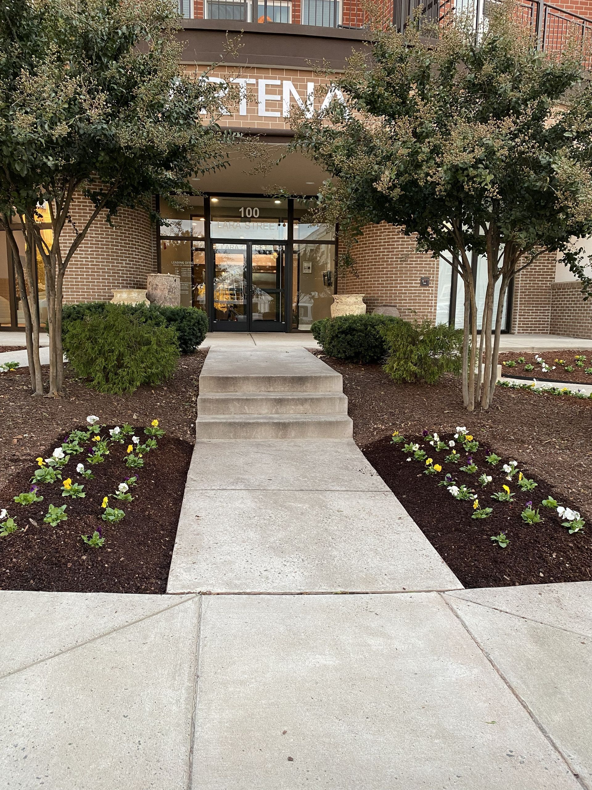 Seasonal color installation at the entrance of an apartment complex, enhancing curb appeal with fresh flowers and landscaping by GreenWish in Northern Virginia