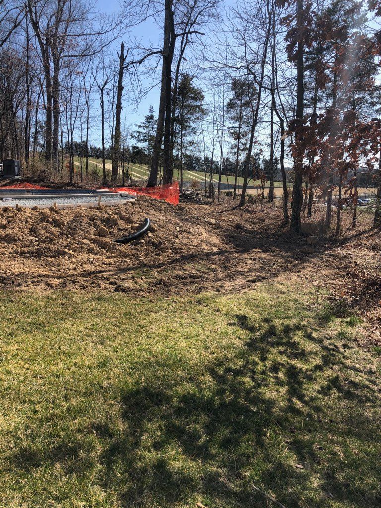Before photo of a residential yard in Northern Virginia showing drainage and grading issues with exposed soil and erosion prior to retaining wall installation by GreenWish