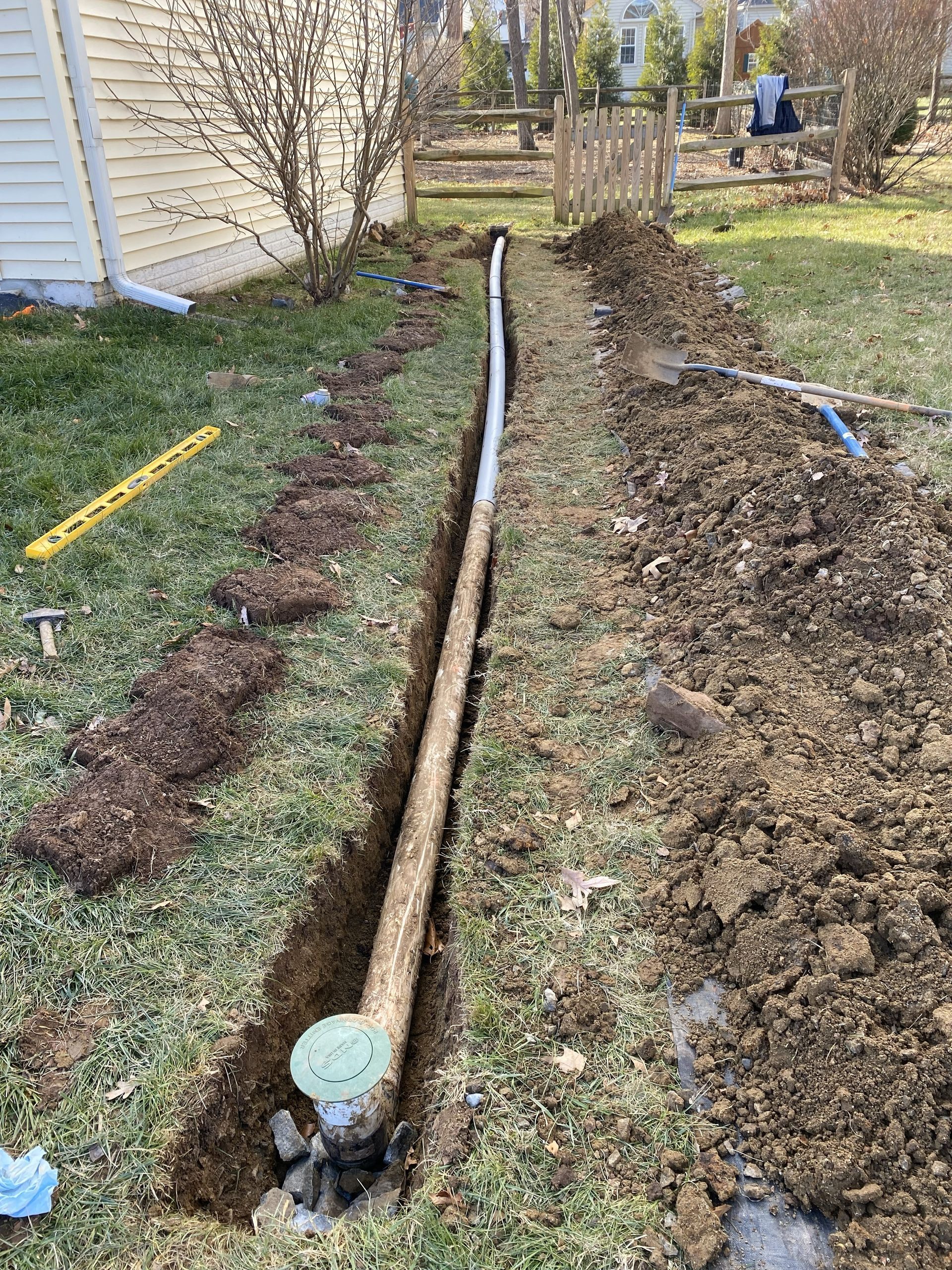 Underground drainage pipe installed to redirect stormwater away from a home and prevent yard flooding in Northern Virginia by GreenWish Landscaping.