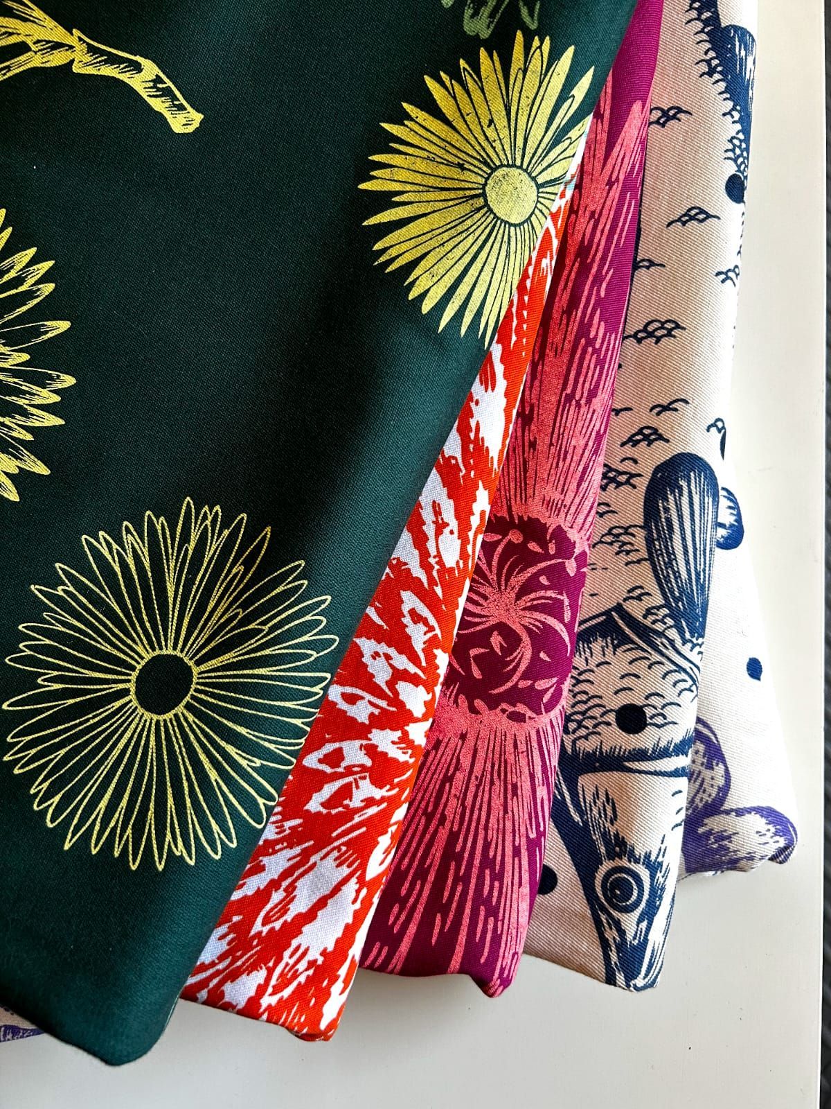 Un montón de telas de diferentes colores están apiladas una encima de otra.