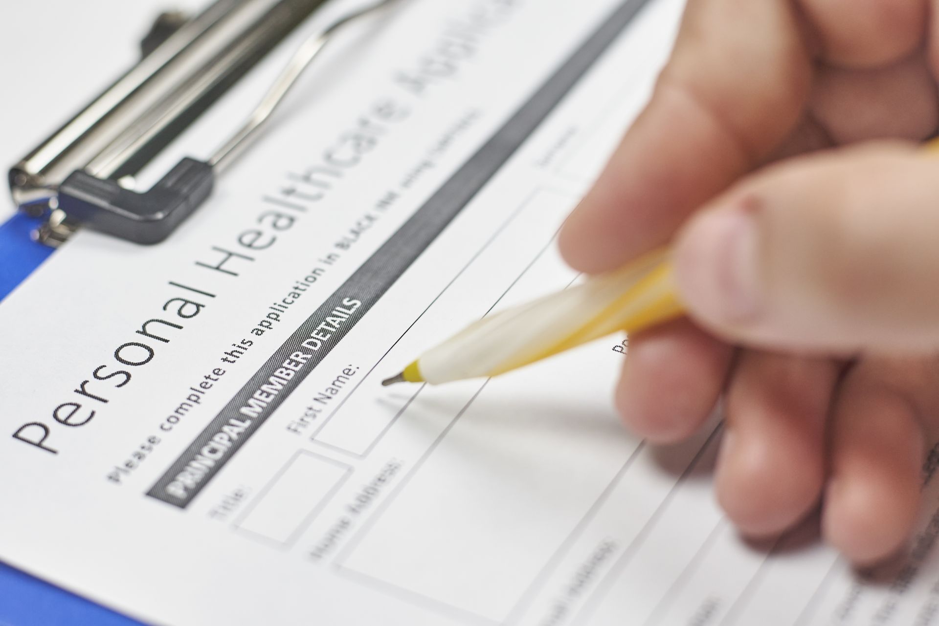 Person filling out a personal healthcare application with a pen.