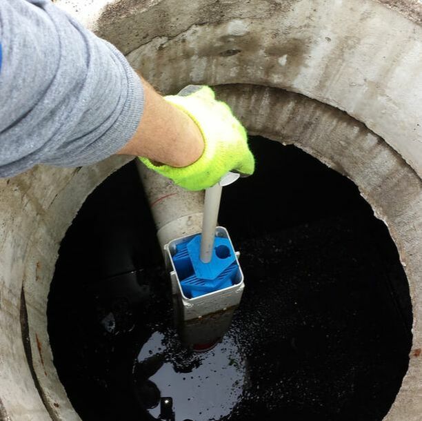 a person is holding a blue box in a manhole