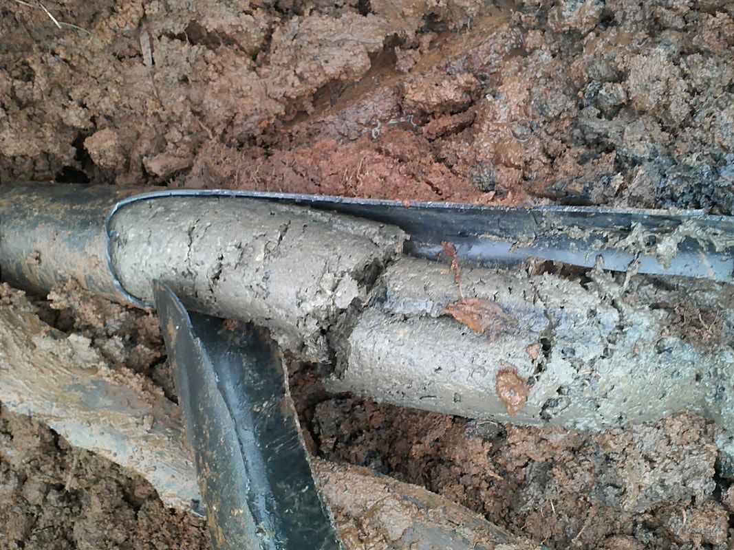 a broken pipe is laying in the dirt next to a shovel