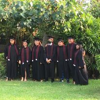 Grupo de personas con togas de graduación posando al aire libre.