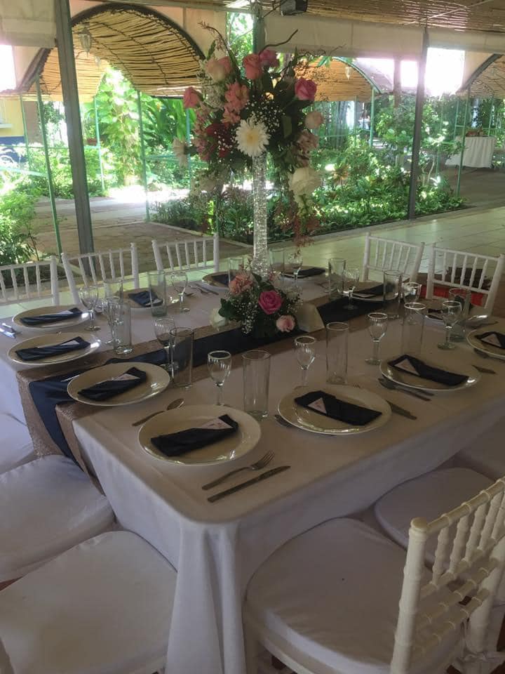 Mesa de recepción de boda preparada con mantelería blanca, flores y servilletas negras.
