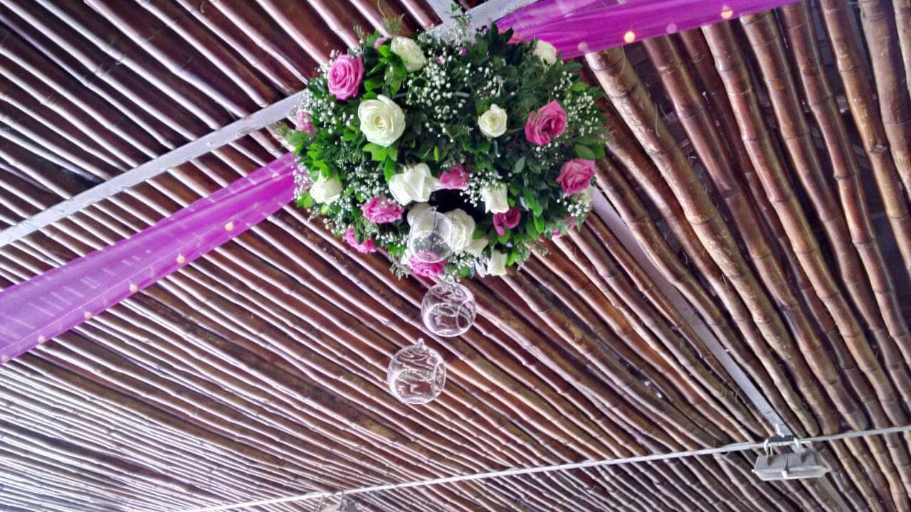 Decoración de bolas florales con orbes colgantes, bajo un techo de madera y tela magenta.