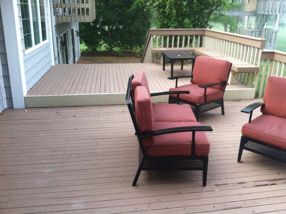 A wooden deck with red chairs and a table