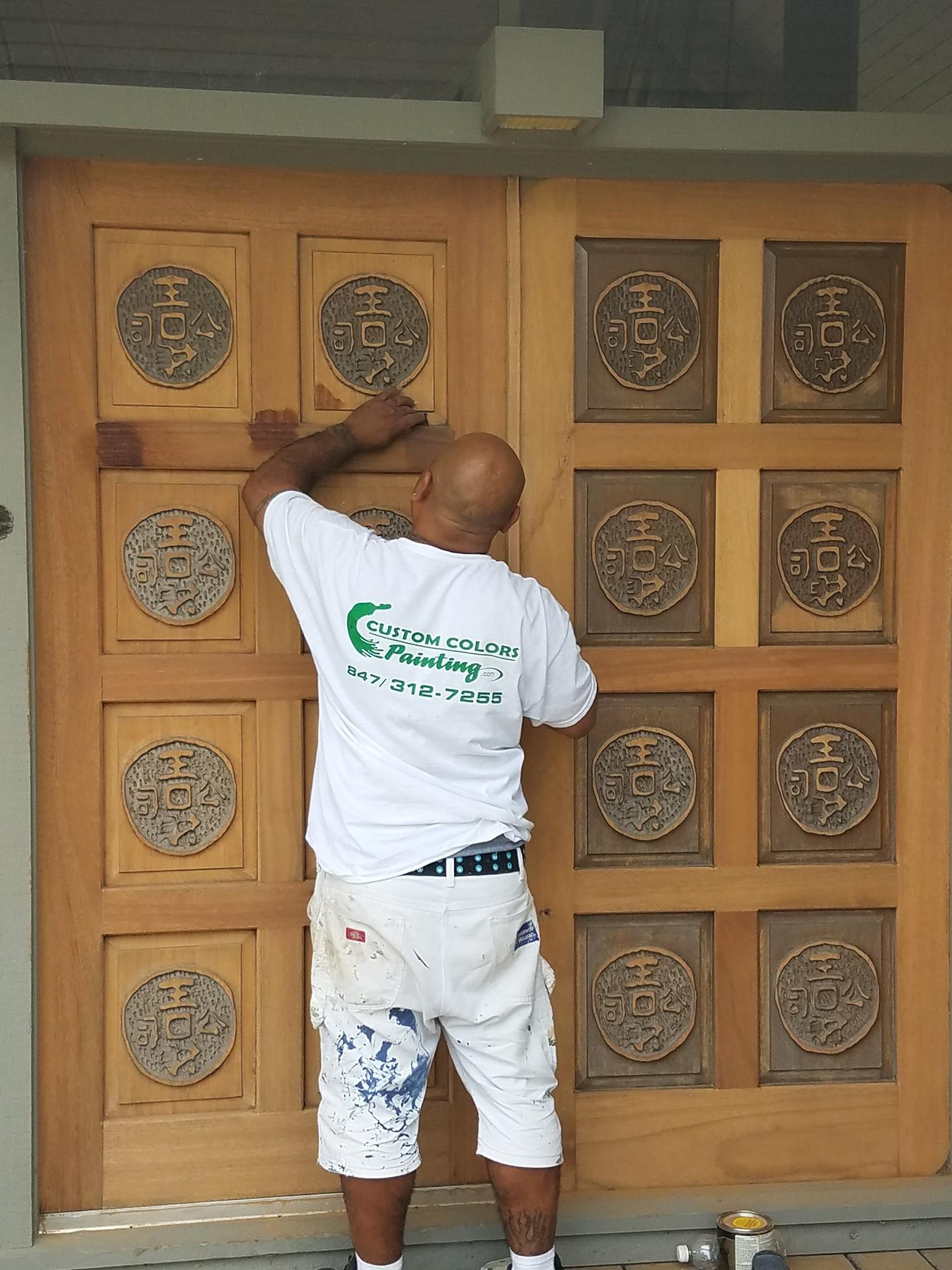 A man is painting a wooden door that says hcs on it