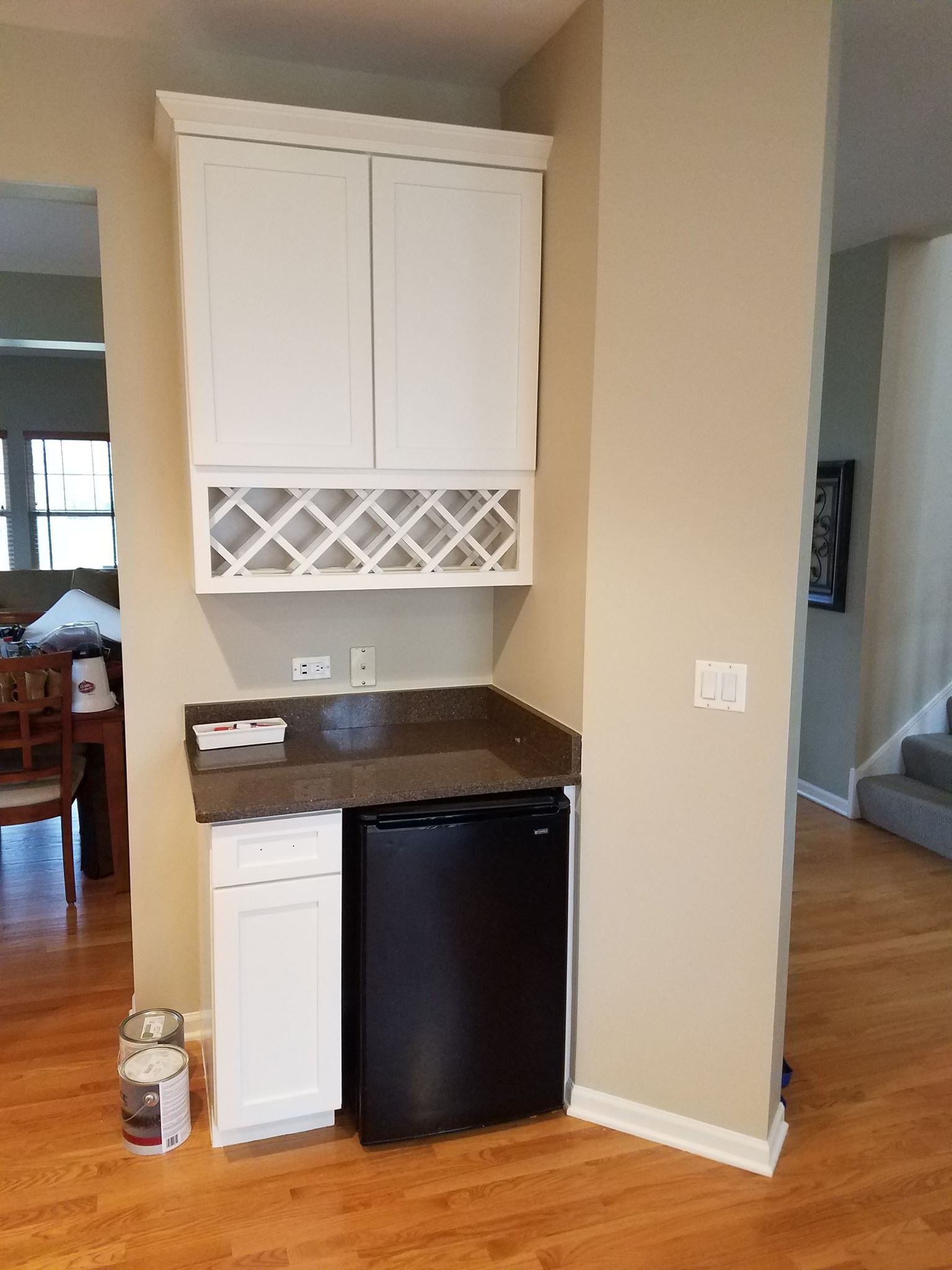 A kitchen with white cabinets and a black refrigerator.
