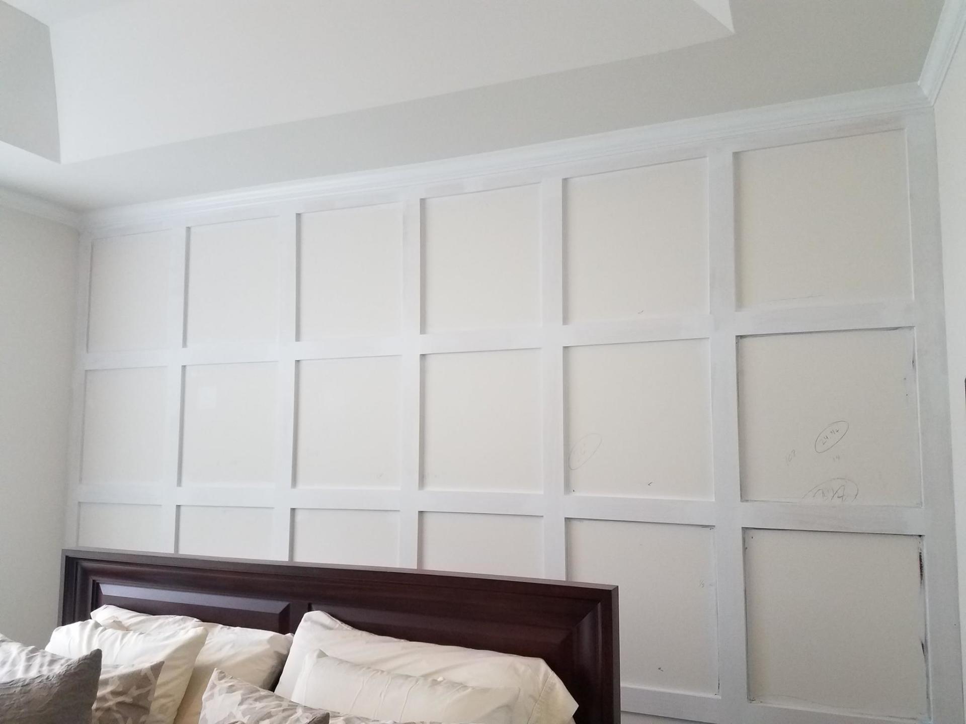 A bedroom with a bed and a wall with squares on it.