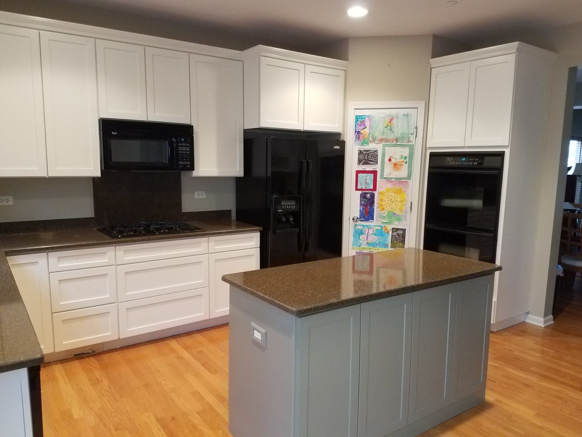 A kitchen with white cabinets , granite counter tops , and a large island.