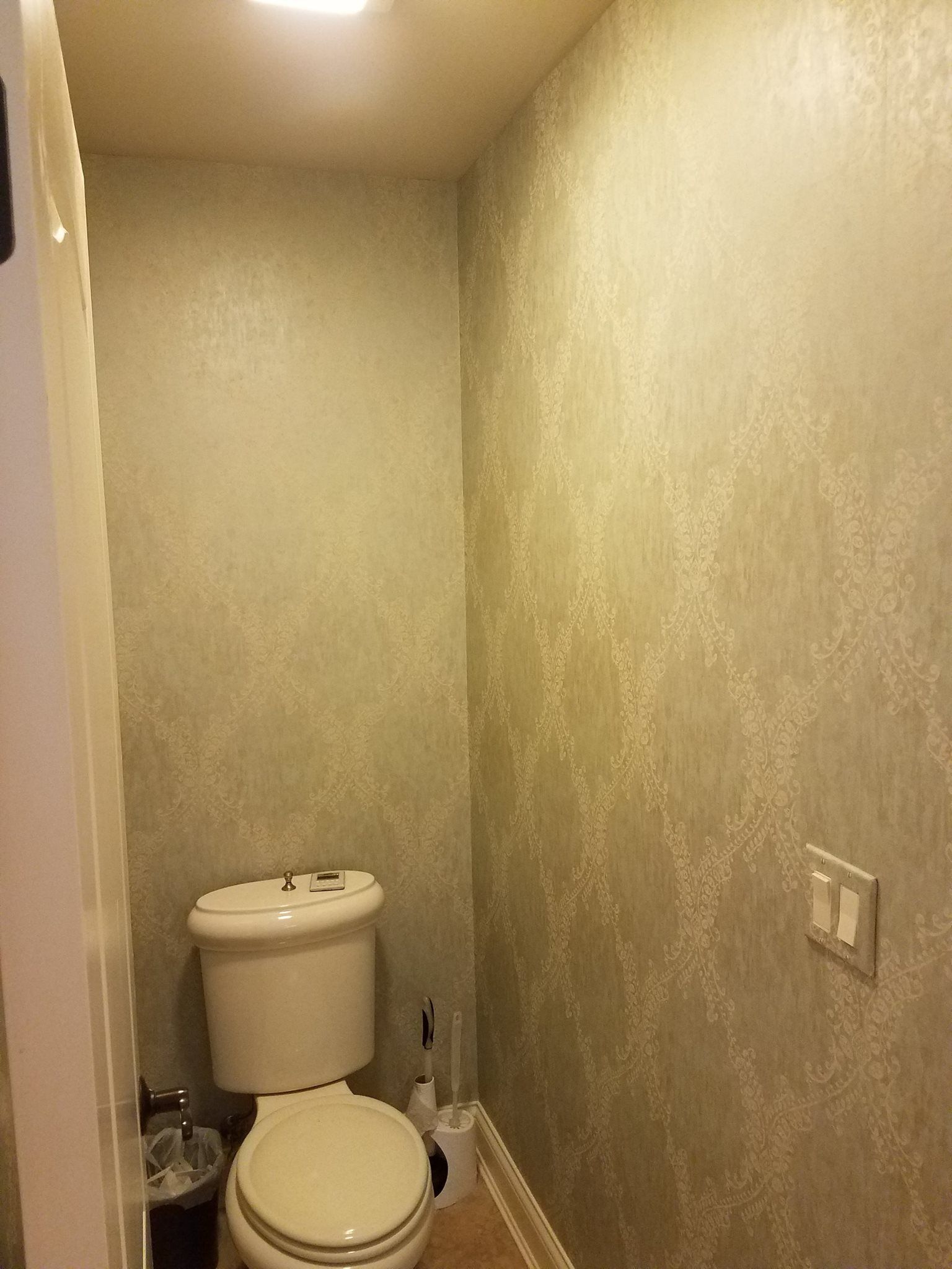 A small bathroom with a toilet and a trash can.