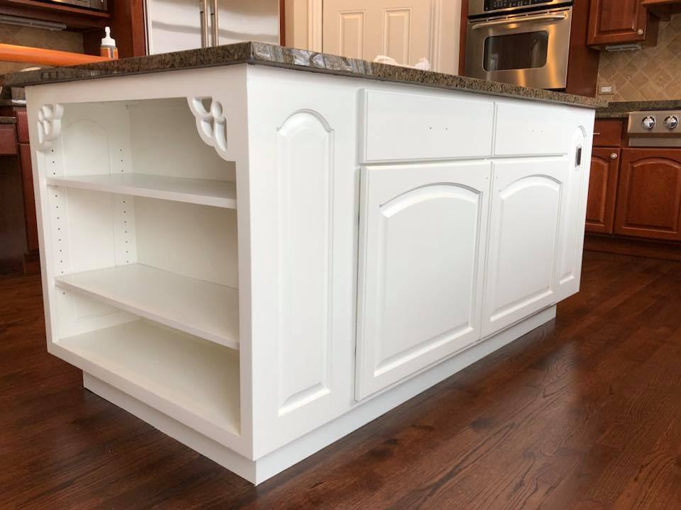 A kitchen island with white cabinets and a granite counter top.