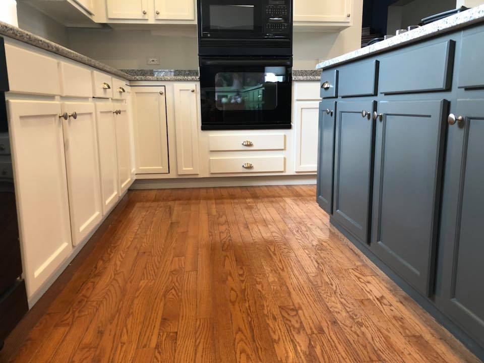 A kitchen with hardwood floors and white cabinets