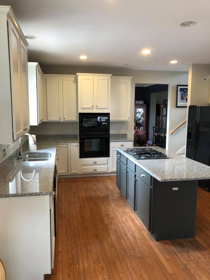 A kitchen with white cabinets and a large island in the middle.