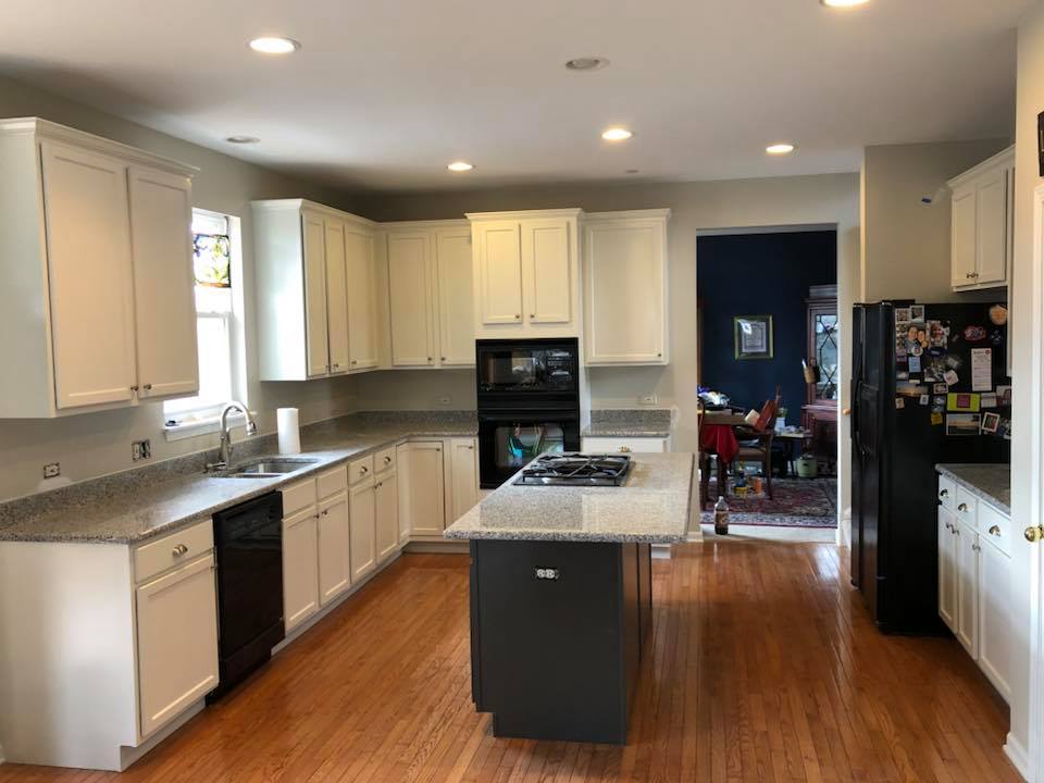 A kitchen with white cabinets , black appliances , and a large island.
