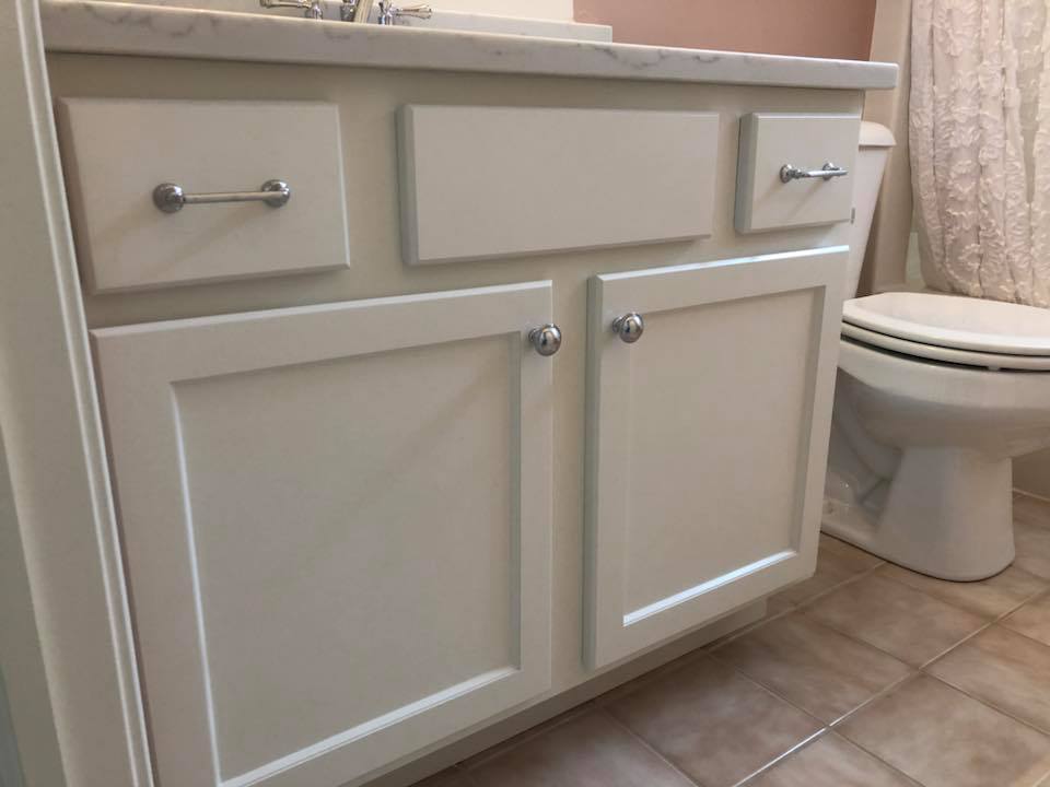 A bathroom vanity with white cabinets and drawers next to a toilet.