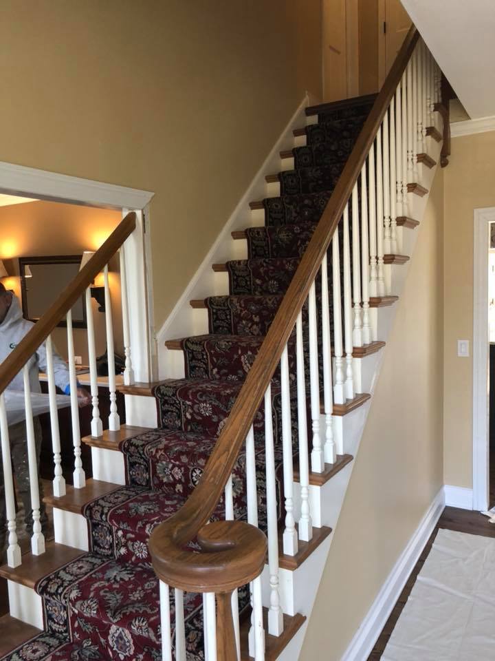 A staircase with a red carpet and white railing