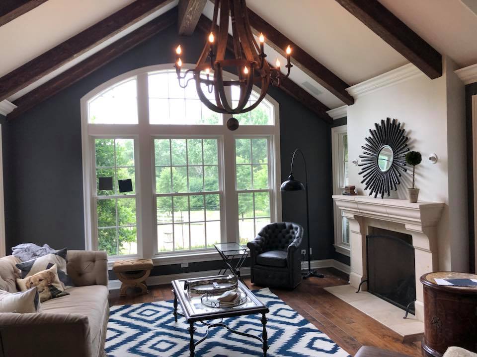 A living room with a fireplace , couch , chair and chandelier.