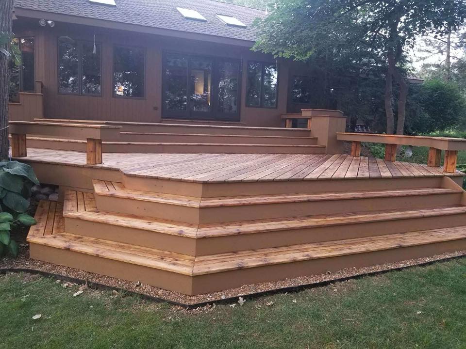 A wooden deck with stairs and a house in the background