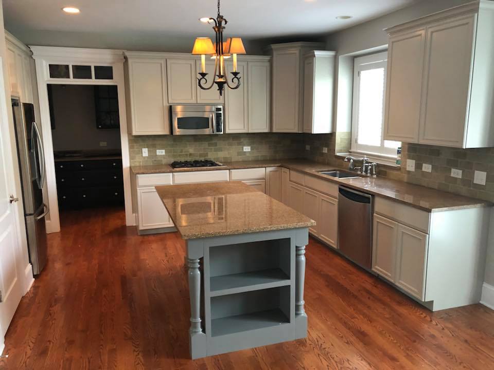 A kitchen with white cabinets , granite counter tops , stainless steel appliances and a large island.