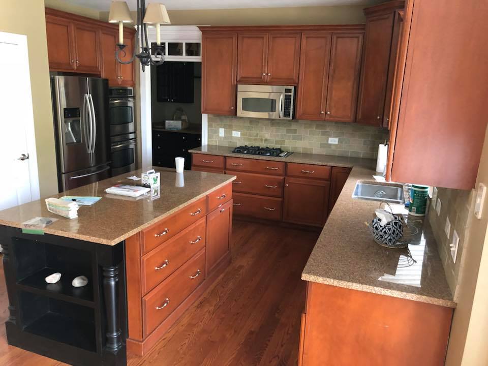 A kitchen with wooden cabinets , granite counter tops , stainless steel appliances and a large island.