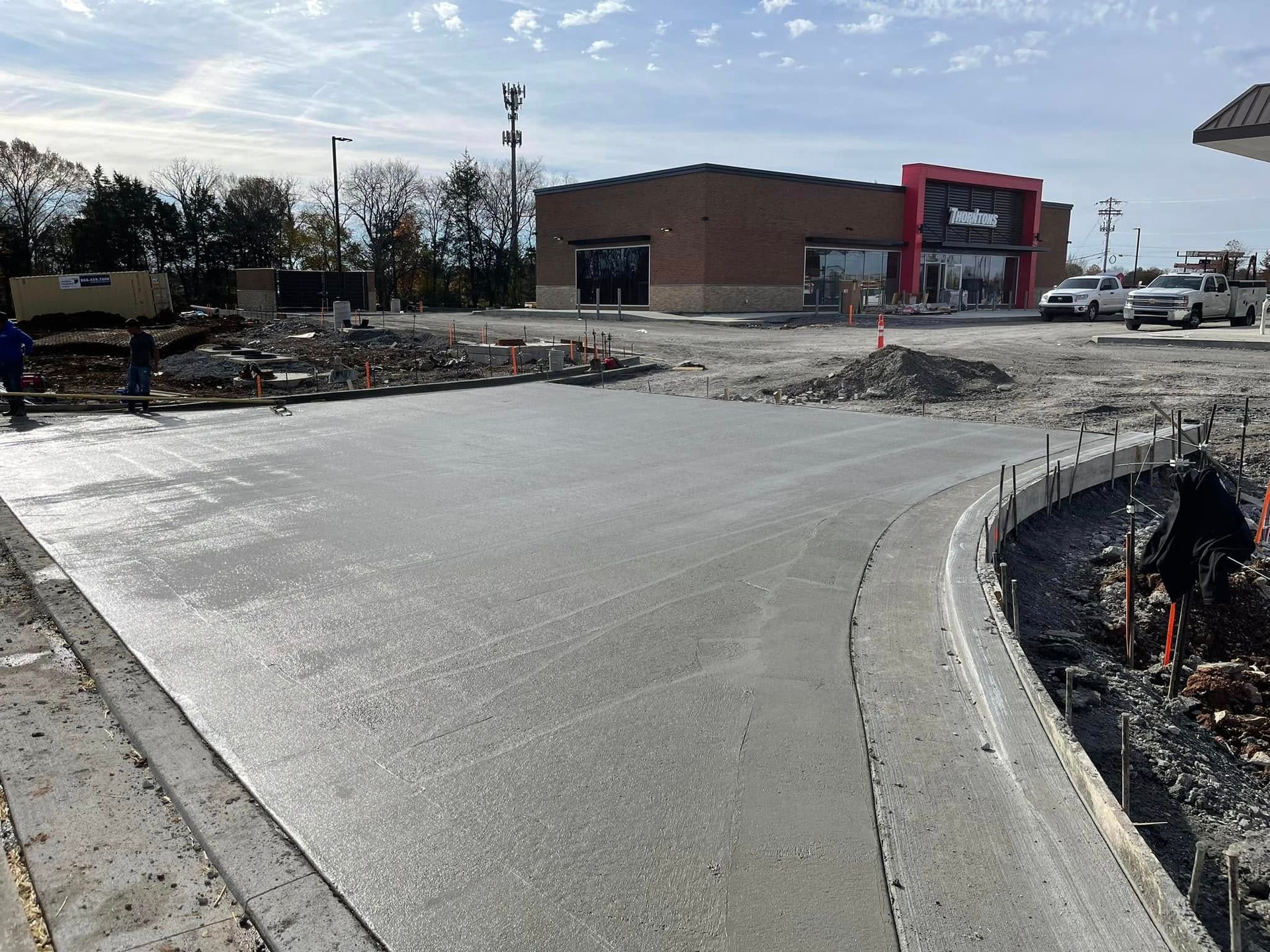 Freshly poured concrete driveway in front of a new brick commercial building under construction on a sunny day.