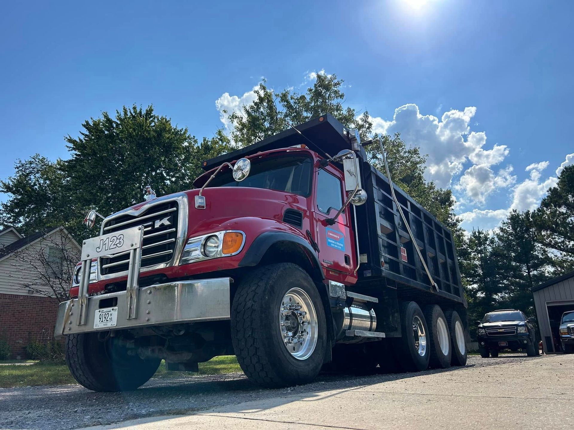 Red dump truck parked outside on a sunny day.