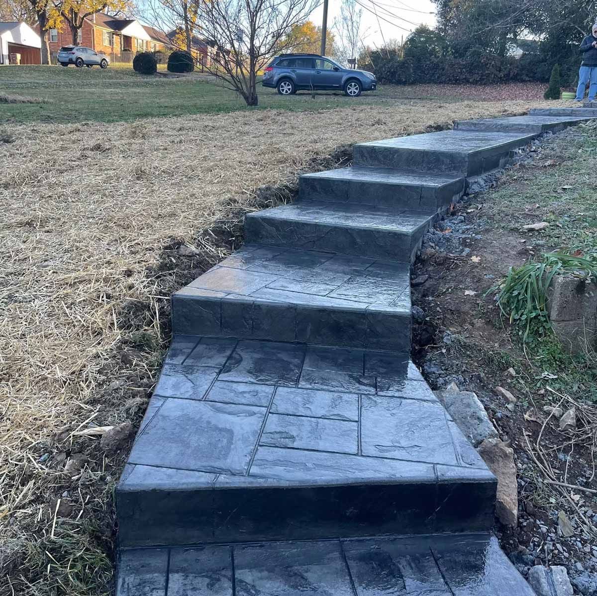 Concrete steps, leading uphill through a yard. Gray stone texture.