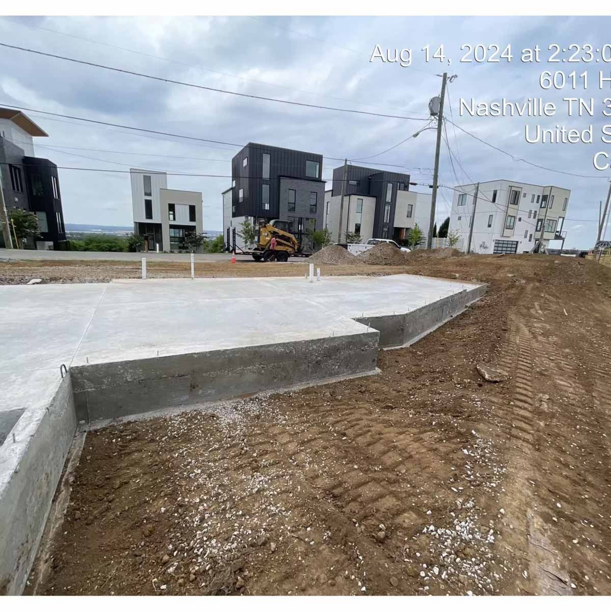Construction site with concrete foundation and modern houses in the background, Nashville, TN.
